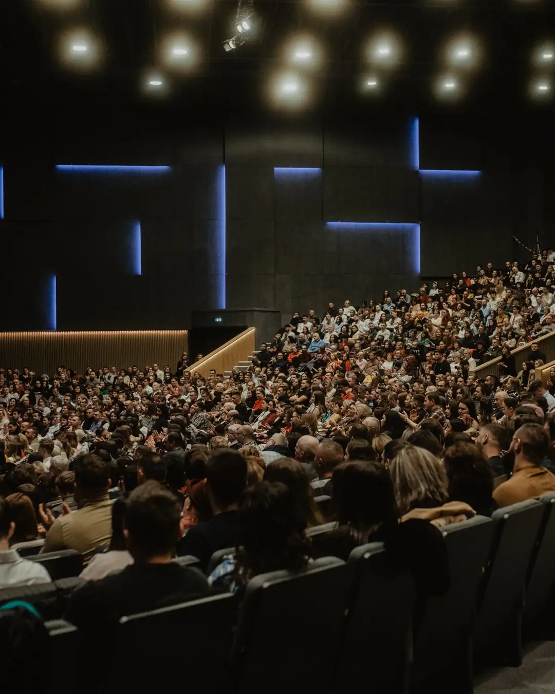 A seated conference audience facing a lit stage