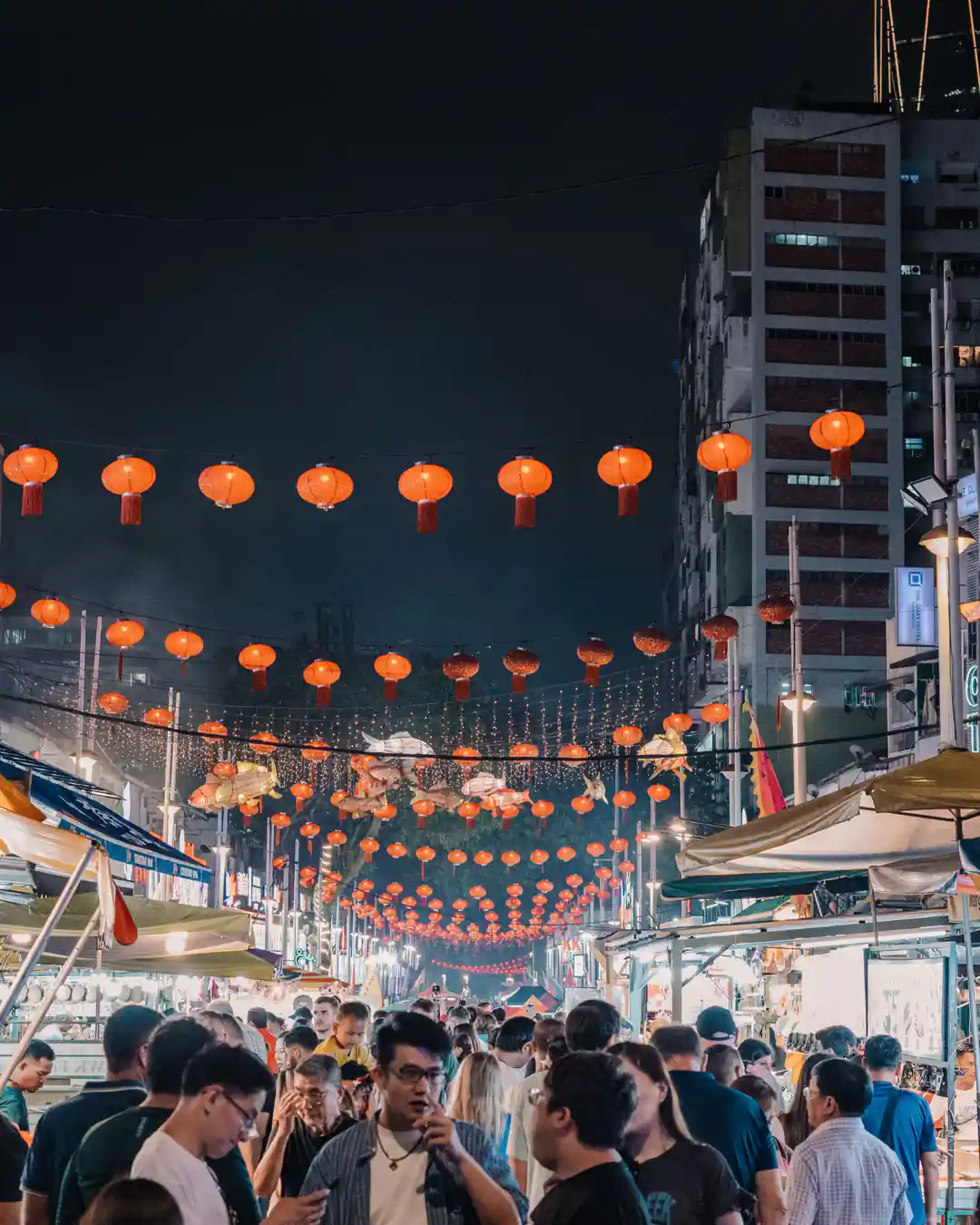 A street food festival crowd under hanging lanterns