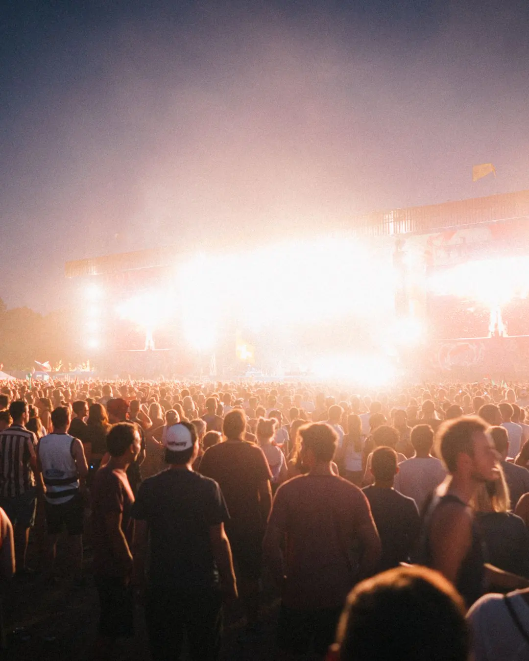 A festival crowd in front of a lit main stage at night